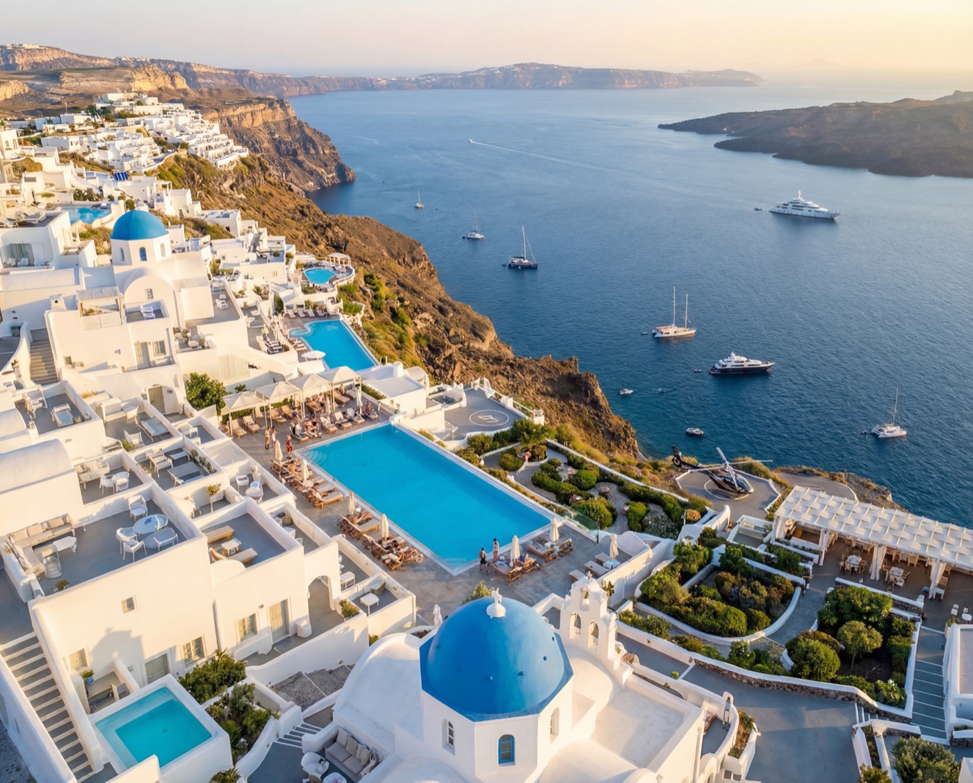 Aerial view of Santorini cliffs, pools, and the sea at sunset
